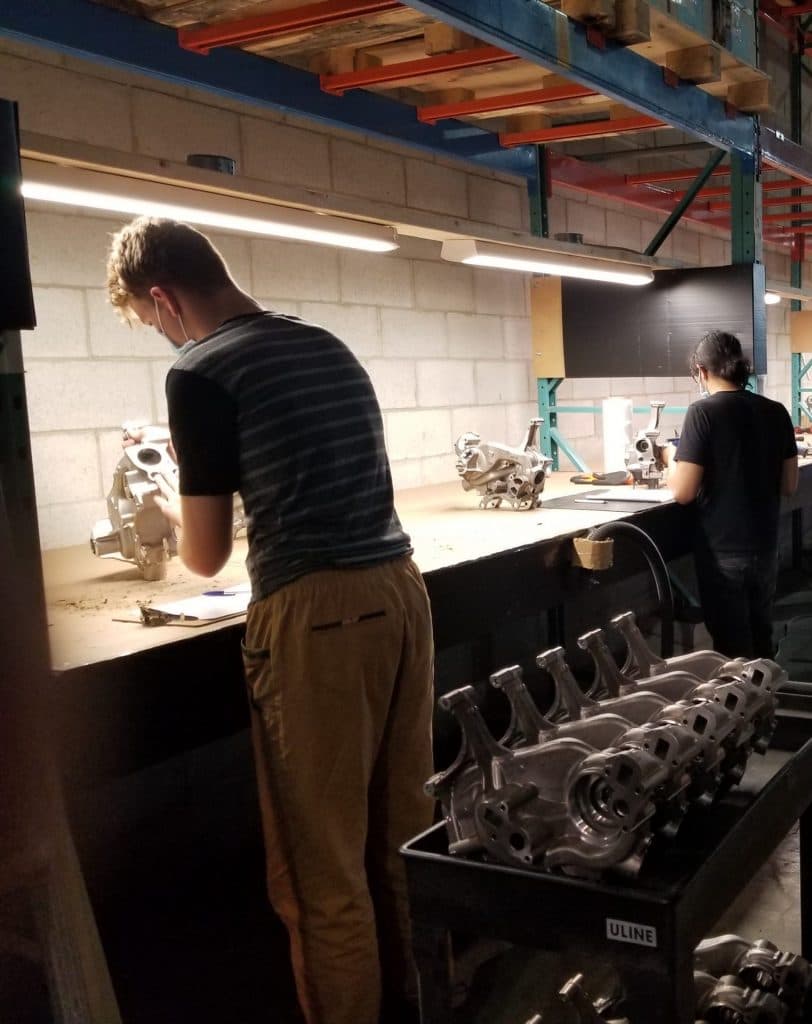Deux opérateurs à un poste d’assemblage chez Les Services Système D, avec des pièces d’aluminium moulées destinées au secteur automobile